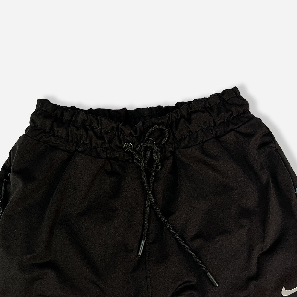 closeup of black trouser with zipper pockets and elastic waistband and nike logo on it.