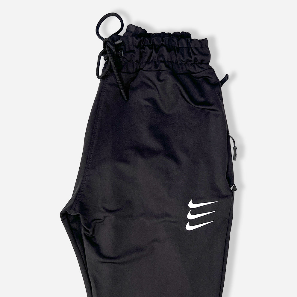 closeup of side packed black trouser with zipper pockets and elastic waistband and nike logo on it.